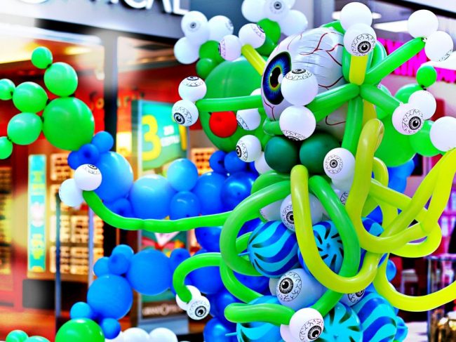 Balónkový mimozemšťan s očima v modro zelené barvě na balónkové výstavě vesmíru. Balónkové UFO s chapadly a očima.