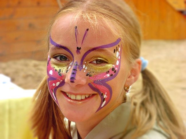 Třpytivý motýlek namalovaný na obličeji holčičky