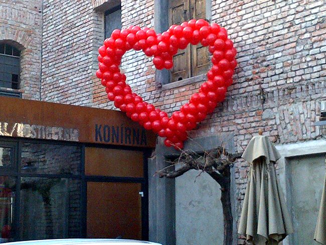 Červené srdce vytvořené z balónků umístěné na stěně restaurace v Praze
