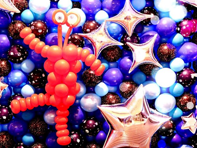 Balónková stěna s červeným mimozemšťanem a stříbrnými hvězdami - balónková výstava vesmír