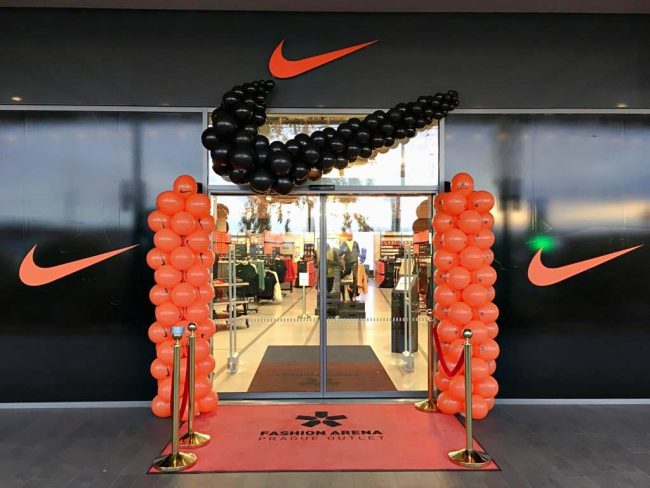 Balónková výzdoba pro firmu Nike, černé balónkové logo a oranžové balónkové sloupy u vchodu do prodejny