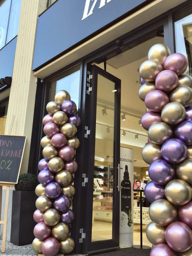 Balónkové sloupy z chromových balónků u vchodu do nově otevřené prodejny v barvách fialová, růžová a zlatá