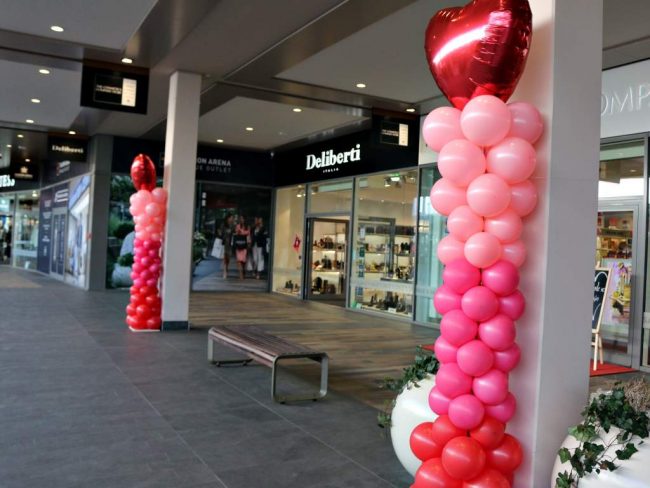 Valentýnské balónkové sloupy z růžových a červených balónků a s fóliovým srdcem umístěným na vrchu sloupu.