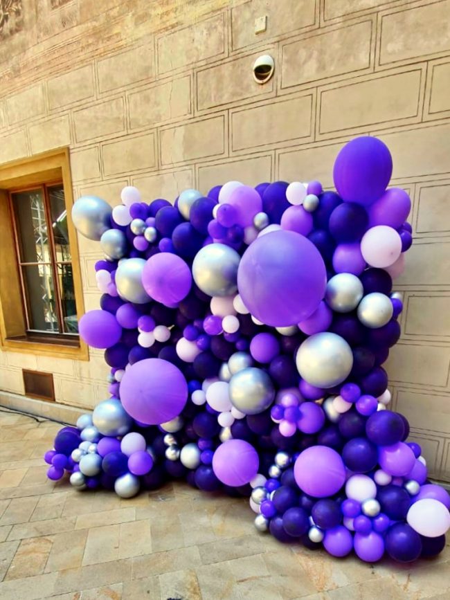 Balónková stěna z fialových balónků různých velikostí jako fotokoutek