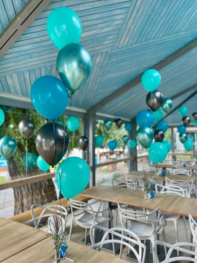 Trsy heliových balónků jako dekorace na stoly v barvě modré, tyrkysové a zelené