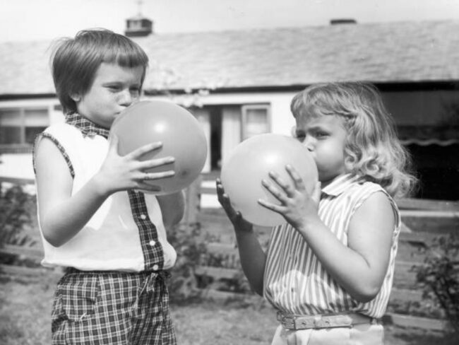 Historie balónků, děti nafukující balónky, černobílá fotka