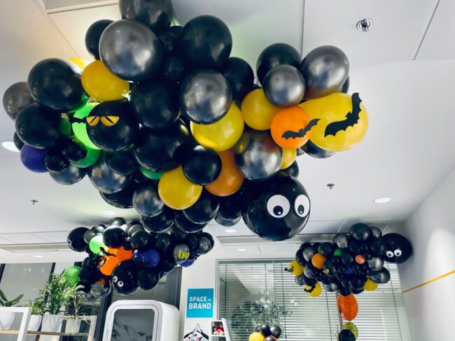 Halloweenská dekorace z balónků ve tvaru pavouka a netopýrů umístěná u stropu