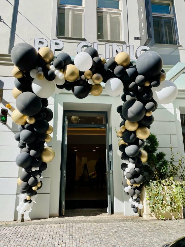 Úžasná balónková dekorace u vstupu do prodejny ze zlatých černých a bílých balónků